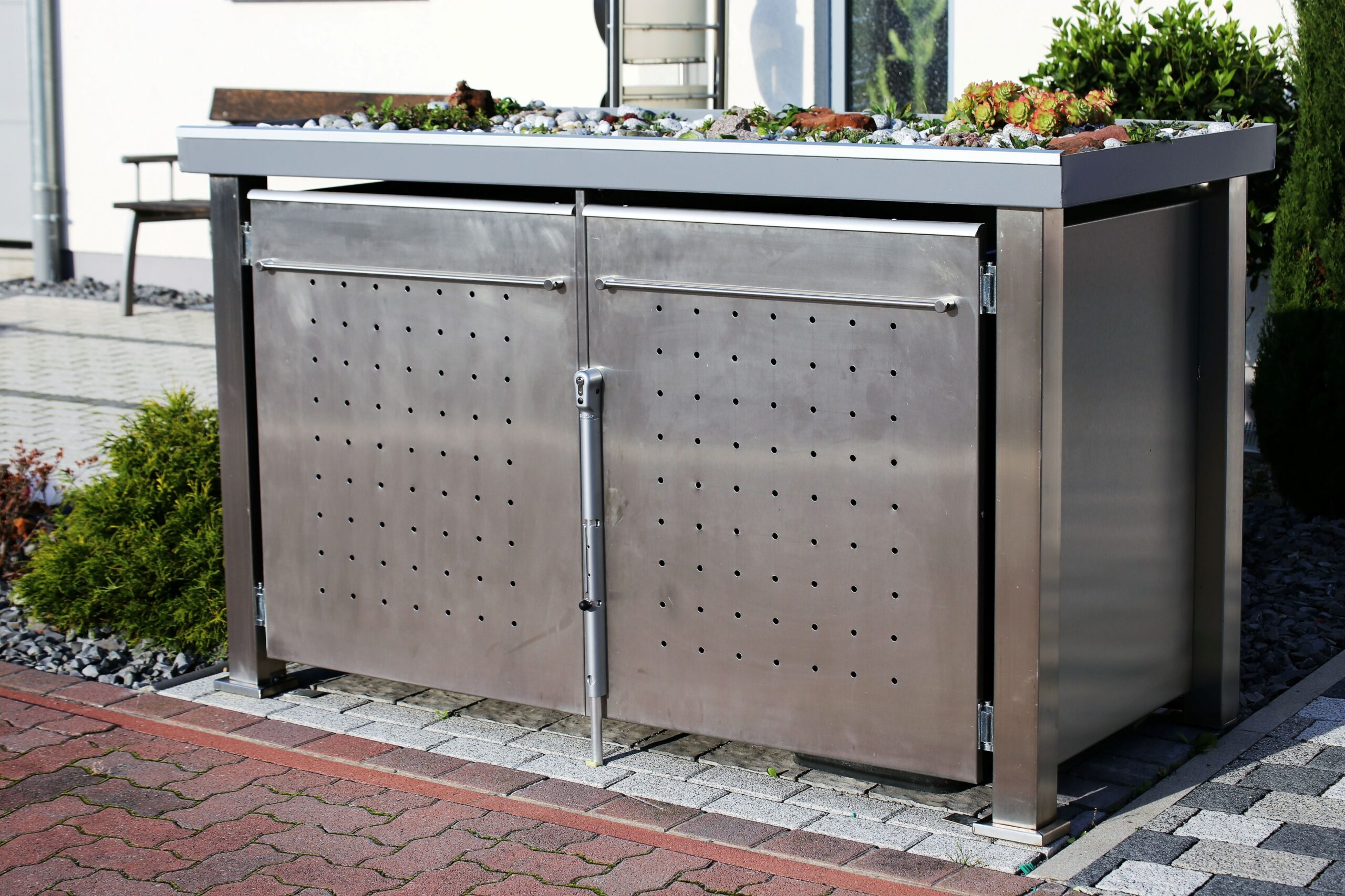 Robuste Mülltonnenbox aus Edelstahl mit begrüntem Dach, wetterfest und modern gestaltet